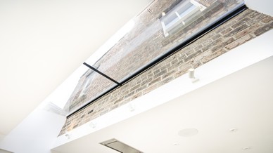Full image of the glass roof light that is connecting the original building to the new extension. The slim profile allows the glass to sit right up against the back wall of the house creating an almost seamless transition from brick to glass.
