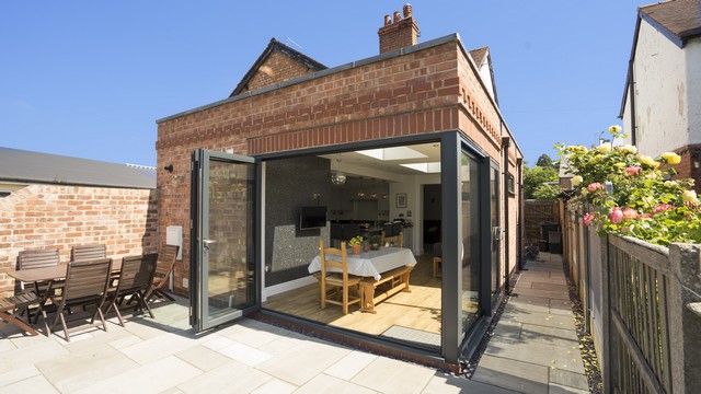 Brick extension with bifolding door in antracite grey opening outwards, with corner post and sliding door.